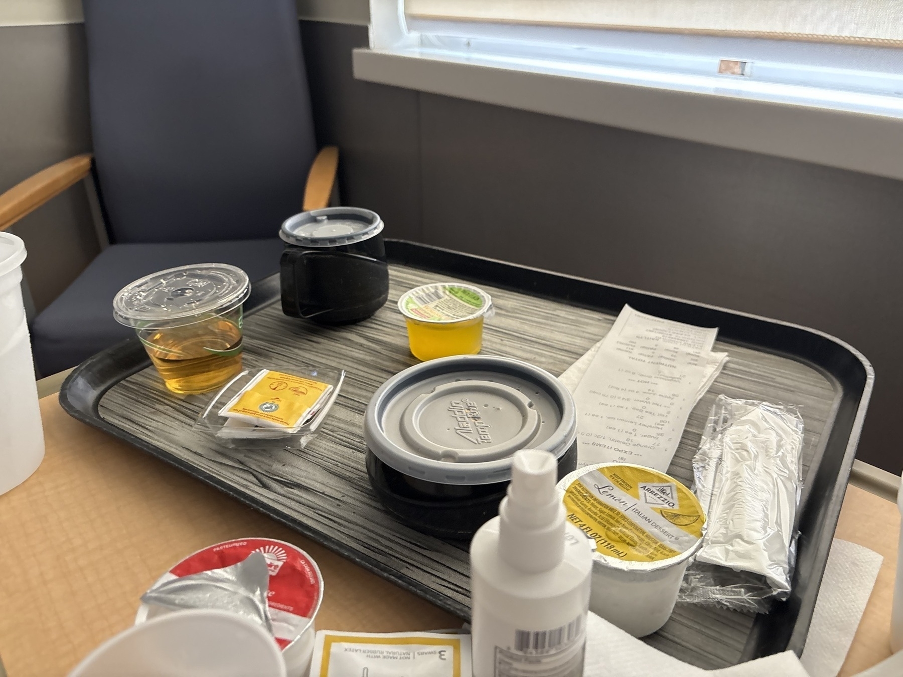 A tray of various liquids in containers on a hospital side table